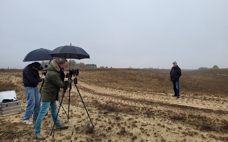 Auf einem Feld wird gearde das Interview gereht. Es regnet ein wenig und es ist sehr bewölkt. 