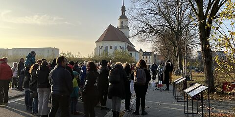 Die Teinehmenden an der Veranstaltung mit etwas Abstand von hinten fotigrafiert, im Hintergrund ist die Stadtkirche St. Nikolai zu sehen.