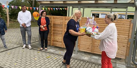 Überreichung eines Präsents auf der Einweihungsfeier vor dem Kita-Gebäude.