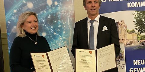 Bürgermeisterin Simone Taubenek und Prof. Dr. Mario Ragwitz vom Fraunhofer IEG Cottbus halten die aufgeschlagenen Mappen mit dem Letter of Intent „Zukunftslabor im neuen Museum“ vor sich in die Kamera.