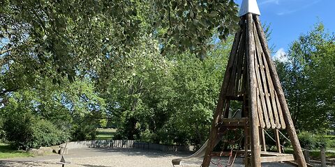 Kletterturm mit der Seite an welcher das Netzt aus roten Seilen zur Kamera gerichtet. Links im Bild ist die Drehscheibe.