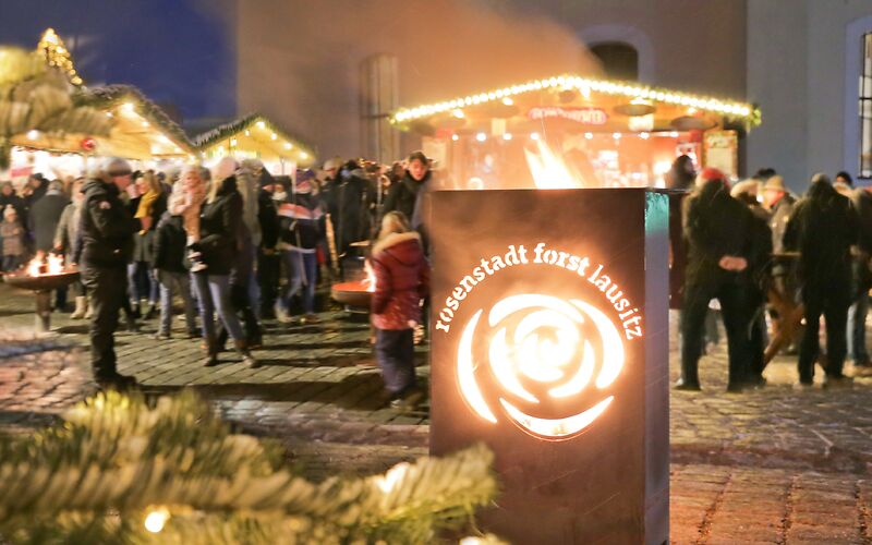 Vorn leuchtet das Rosen-Logo der Stadt Forst mit dem Schriftzug 